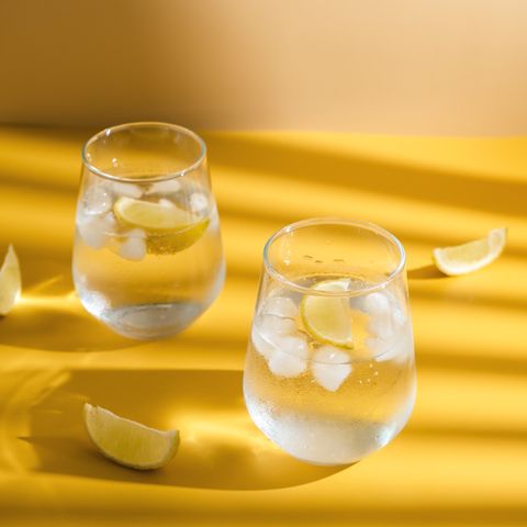 refreshing sparkling drink with ice cube on a yellow background