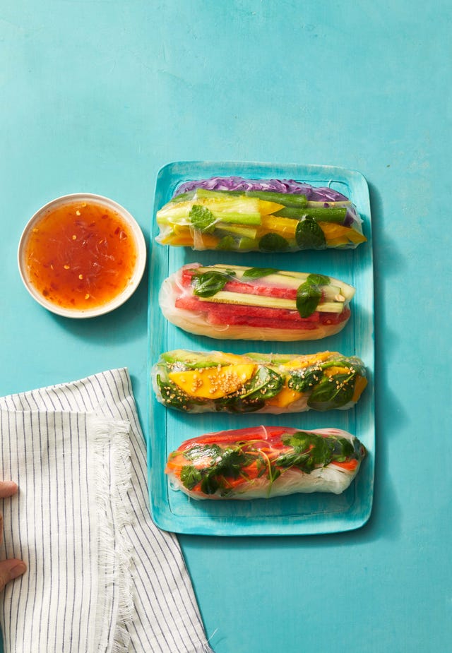 four summer rolls with veggie matchsticks wrapped in rice paper on a blue plate
