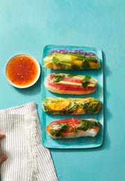 four summer rolls with veggie matchsticks wrapped in rice paper on a blue plate