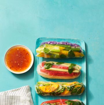 four summer rolls with veggie matchsticks wrapped in rice paper on a blue plate