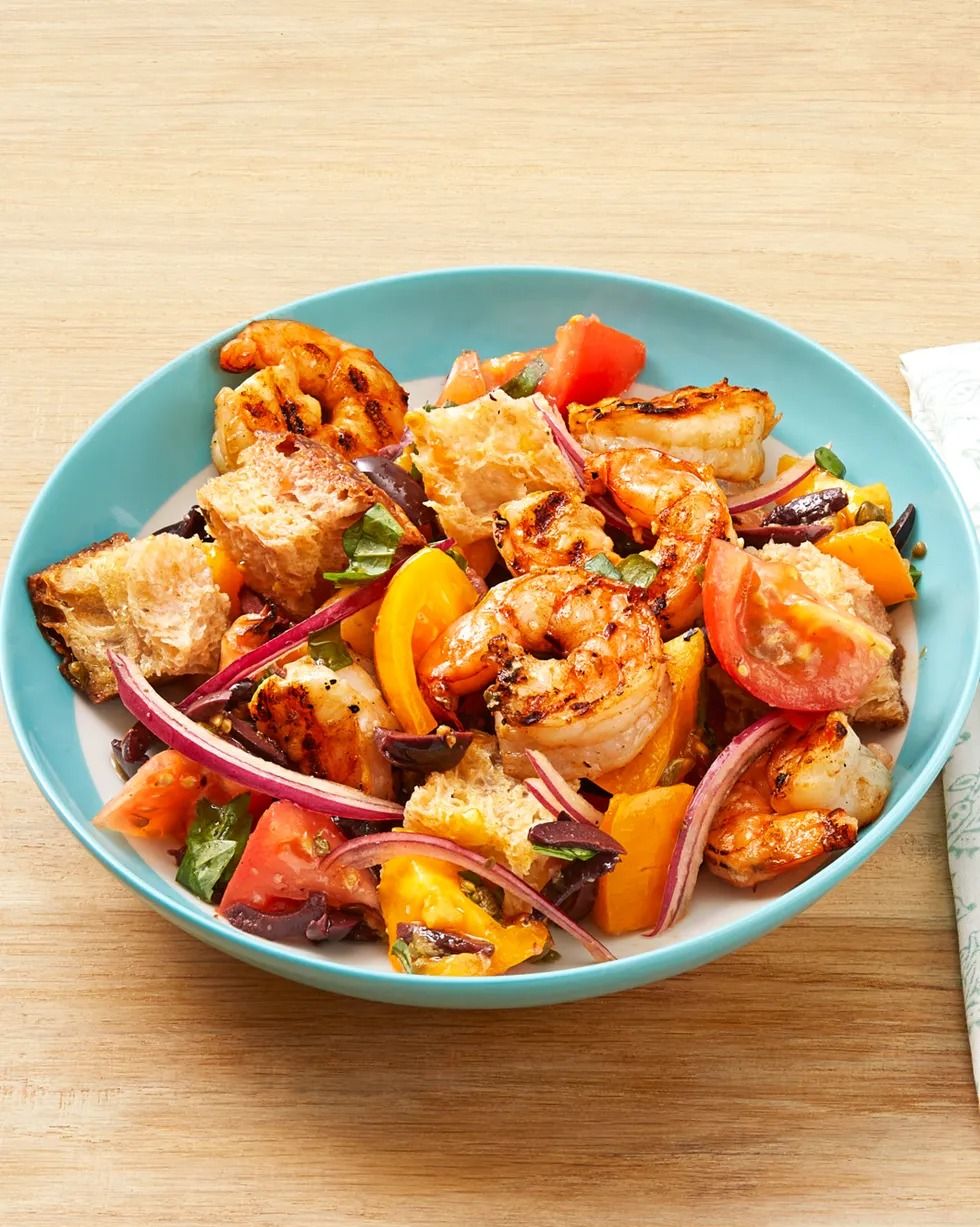 grilled shrimp panzanella with tomatoes and red onions in bowl