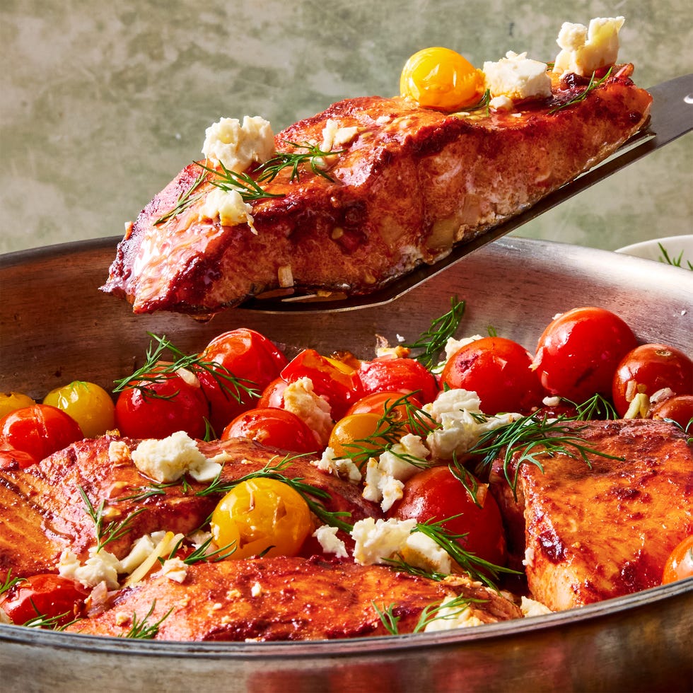 Les filets de saumon sont saupoudrés de cumin et de paprika, frottés avec de la pâte d'harissa épicée et rôtis avec des tomates cerises, des échalotes et de l'ail, puis garnis d'aneth frais et de feta crémeuse.