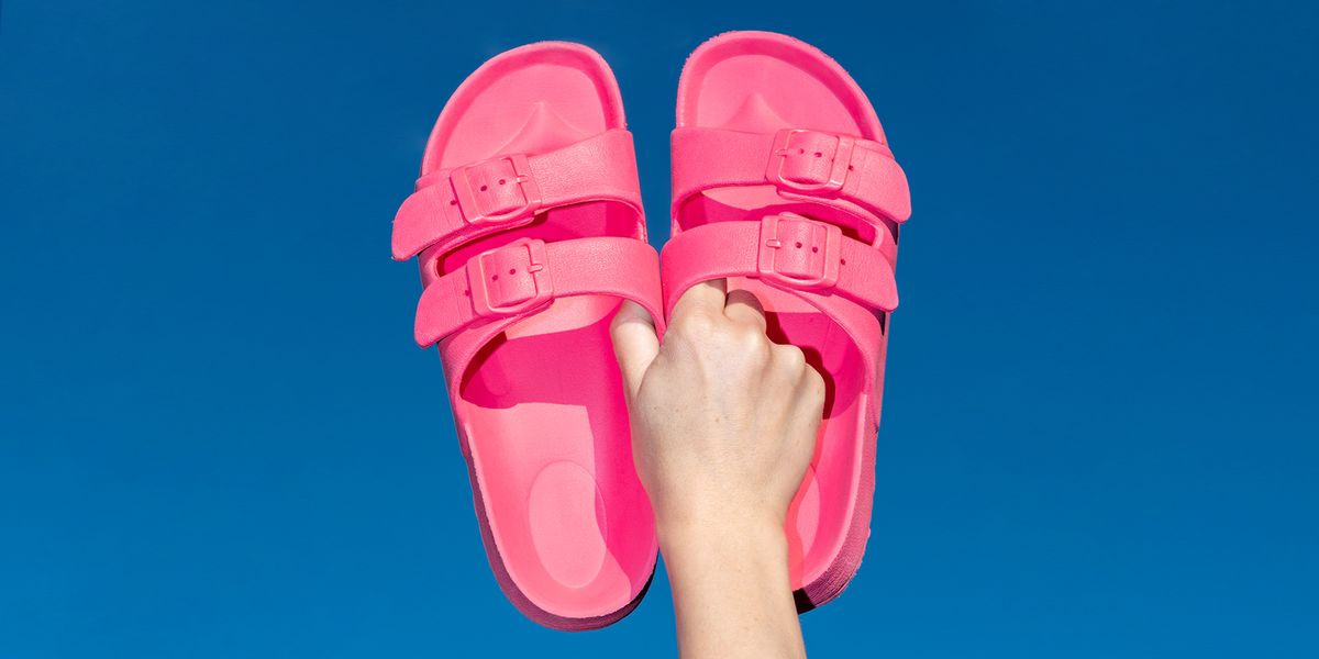 hand holding pink birkenstock sandals against sky