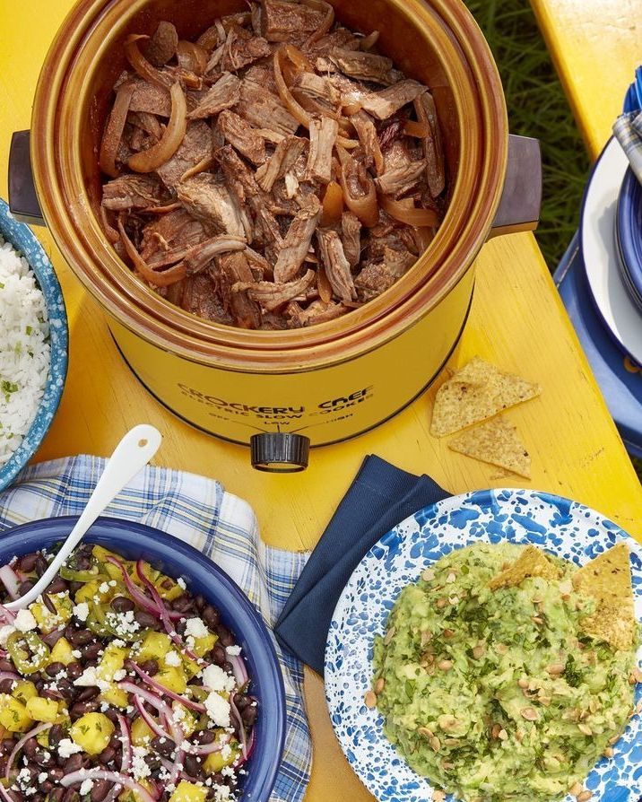 smoky slow cooker beef tacos in a slow cooker on a table with side dishes