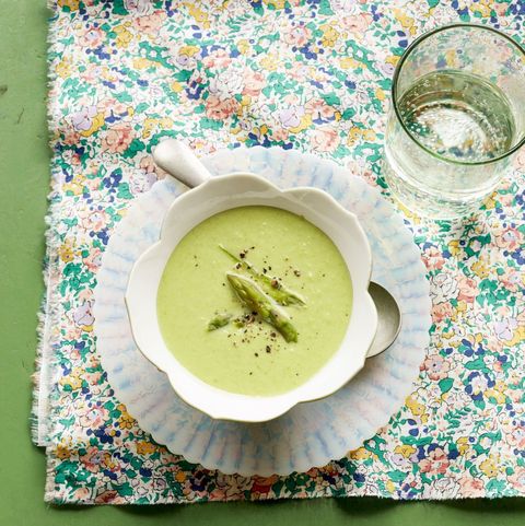 cream of asparagus soup in white bowl with asparagus tips