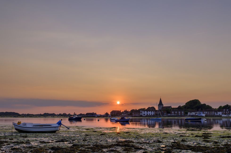 Summer sunset over Bosham Harbour and village with the church spire of Holy Trinity Church, West Sussex, UK