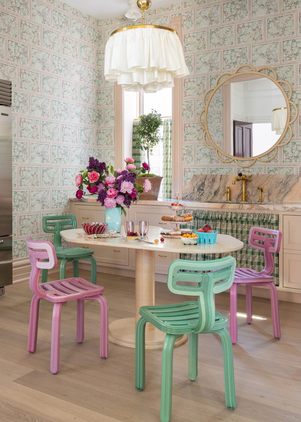 a pastel colored kitchen with vintage wallpaper, marble countertops, and eclectic decor