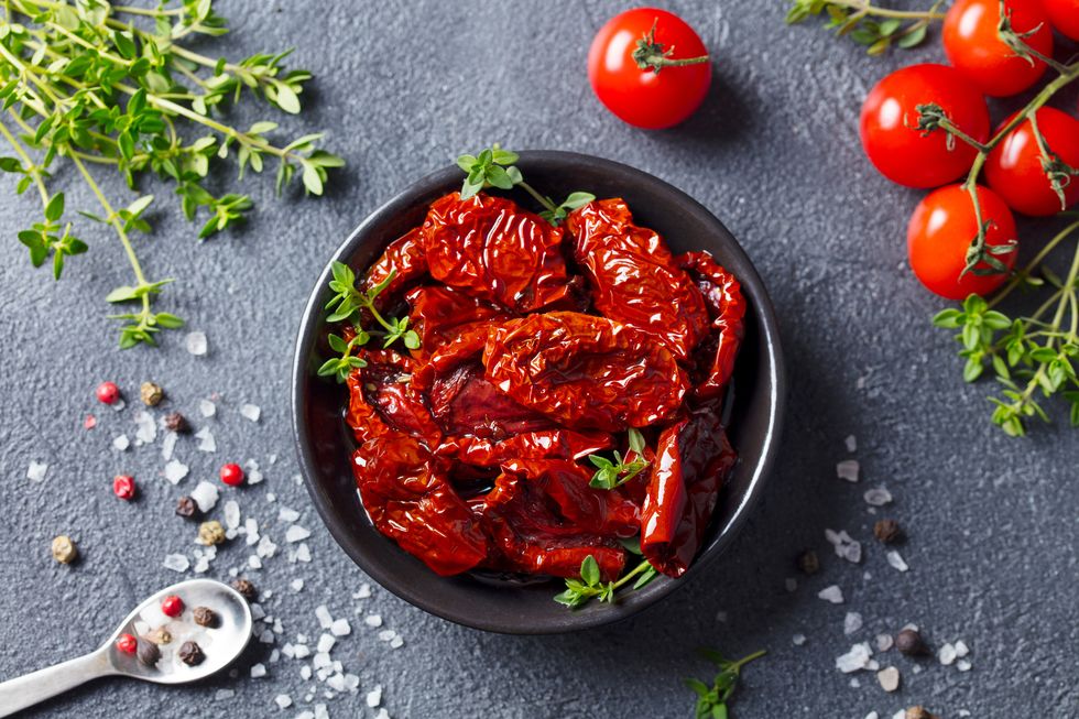 sun dried tomatoes with fresh herbs and spices slate background top view