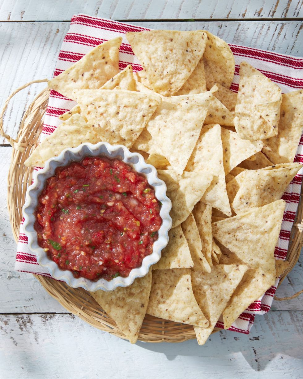 garden salsa in a small bowl on a woven tray with tortilla chips