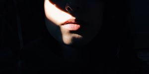 sunlight falling on lips of woman in darkroom
