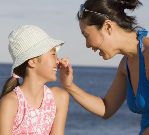 mother applying sunscreen to daughter nose