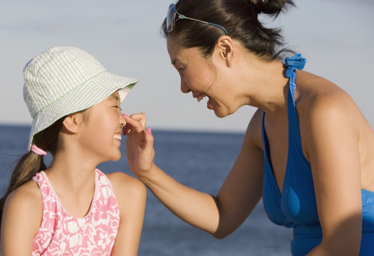 mother applying sunscreen to daughter's nose