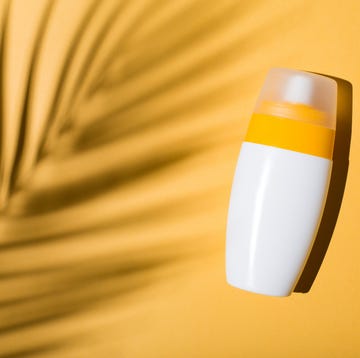 sunscreen on a yellow background with shadow of tropical leaf flat lay, top view