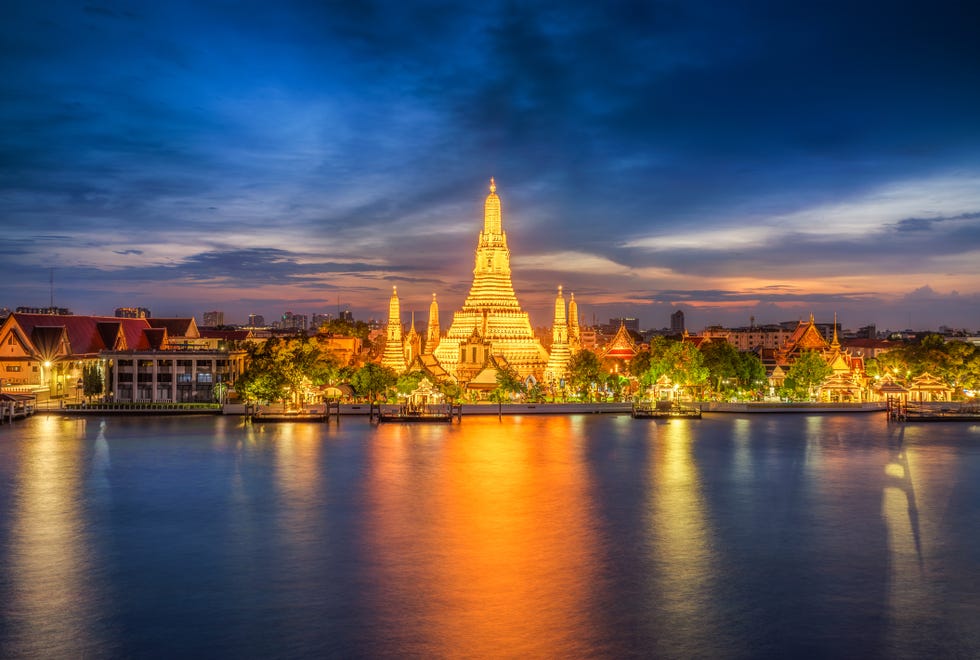 sunset city skyline at wat arun temple and chao phraya river, bangkok thailand,