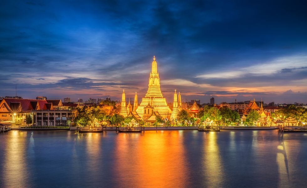 sunset city skyline at wat arun temple and chao phraya river, bangkok thailand,