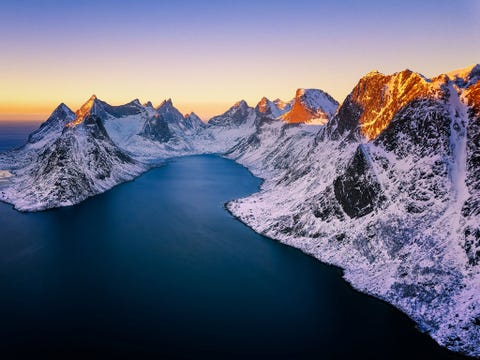 https://www.nationalgeographic.com/content/dam/travel/rights-exempt/2018-travel-photographer-of-the-year/magical-mountains/sunset-reine-lofoten-norway.jpg Luchtfoto van een zonsondergang boven het dorp Reine op de Lofoten Noorwegen