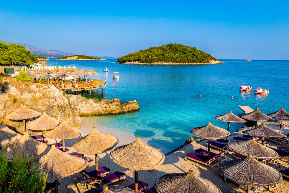 sunshade umbrellas, deckchairs and boats on the beautiful ksamil beach, vlore, ionian sea, albania, balkans, europe