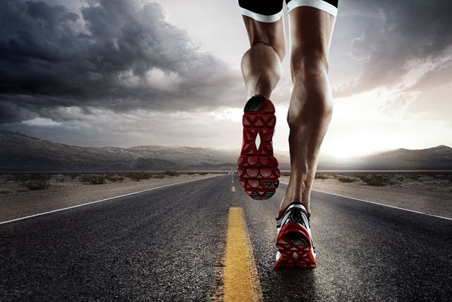 low angle view of male runners legs running down road wearing trainers
