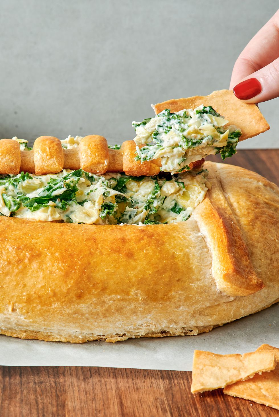 spinach and artichoke dip in a bread bowl shaped like a football