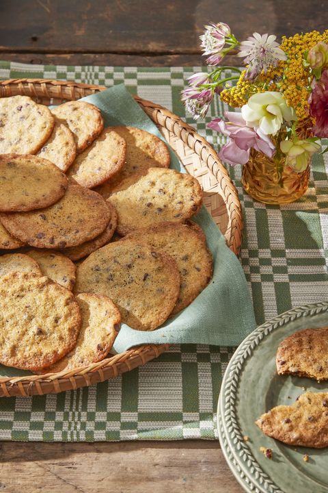 thin and crispy chocolate chip cookies in a basket lined with a tea towel