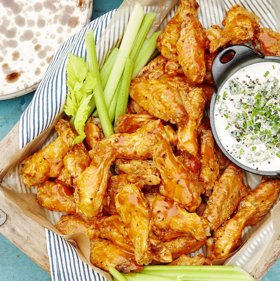 a plate of buffalo wings with dip and celery