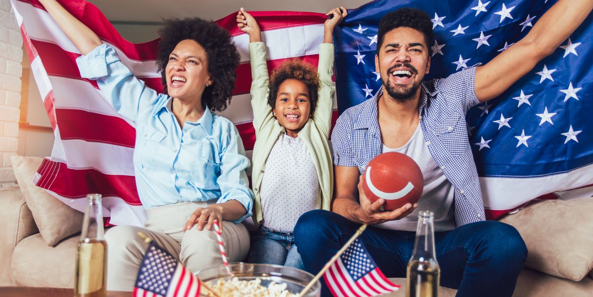 super bowl party ideas, family of three watching tv and cheering sport games on sofa at home