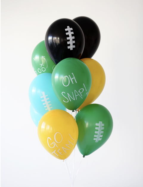 super bowl party ideas, green, yellow, blue and black balloons tied together with words written on the front