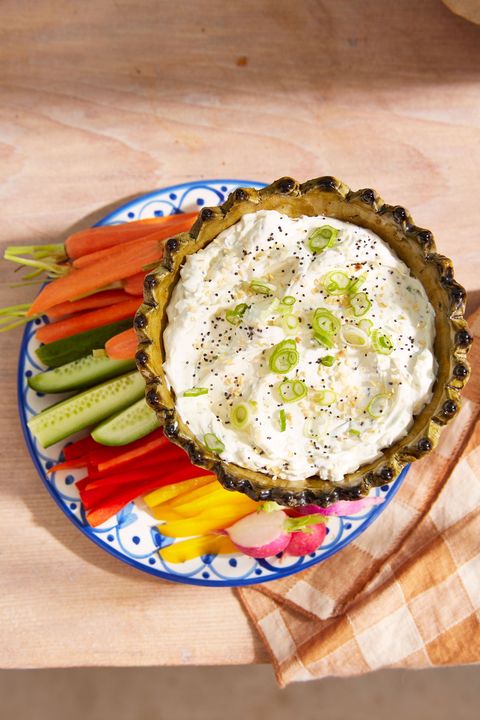 everything bagel dip in a bowl on a plate with various veggies for dipping