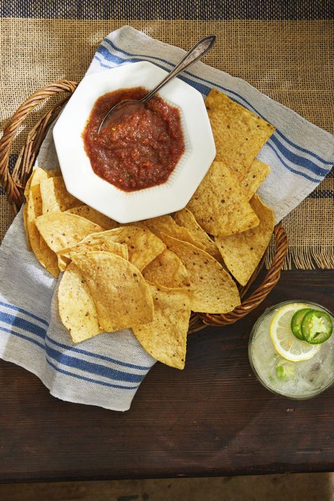 restaurant style salsa in a white bowl in a basket of tortilla chips