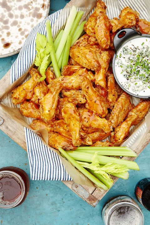 spicy oven baked wings on a wooden serving tray with celery sticks and a small bowl of blue cheese dip
