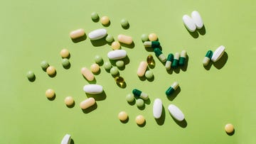 colorful pills and capsules on green background minimal medical concept flat lay, top view