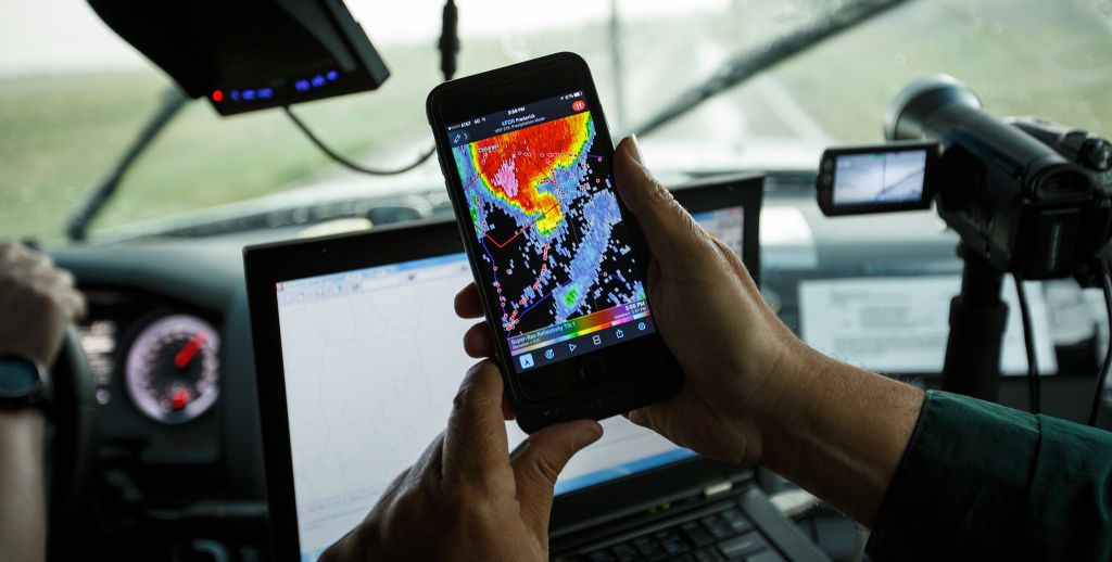 center for severe weather research scientists search for tornadoes to study, man viewing weather app on smartphone