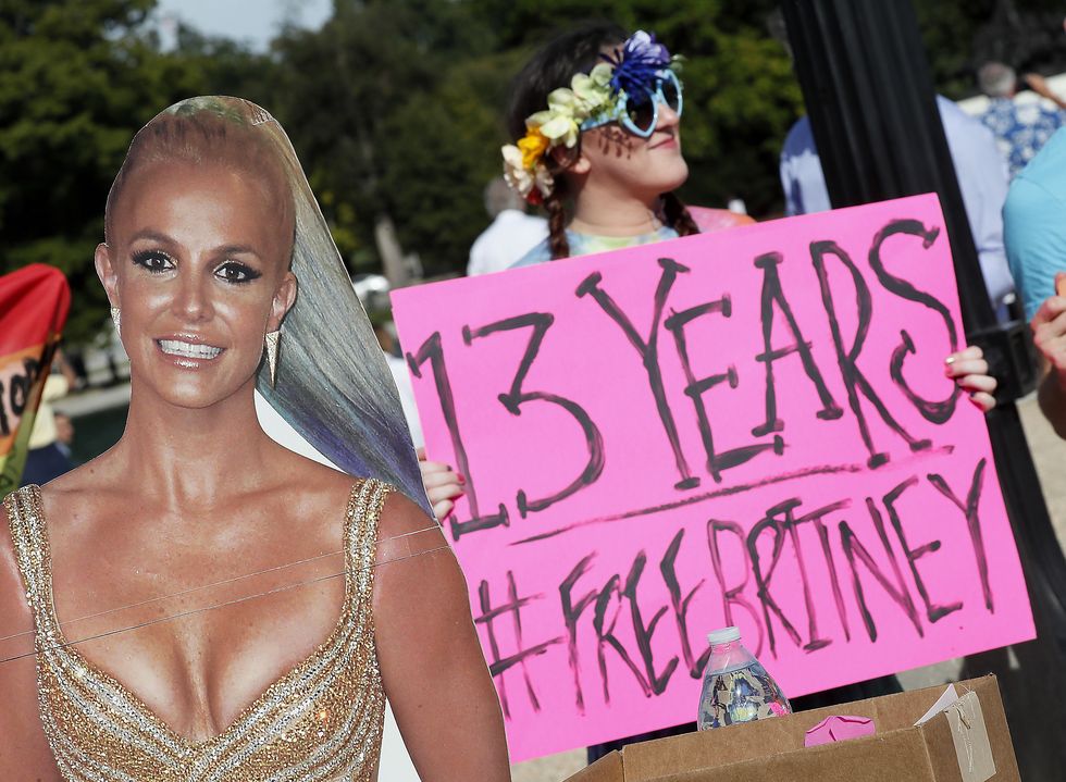 a brtiney spears cutout next to a fan holding a sign that says free britney