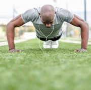 Surface Level View Of Man Doing Push-Ups On Grassy Field
