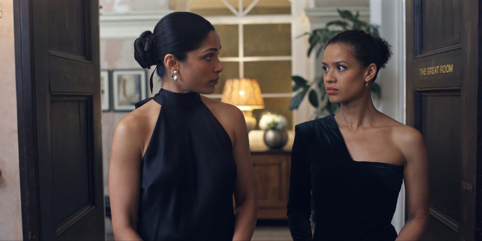 two women in elegant attire standing near a door labeled the great room