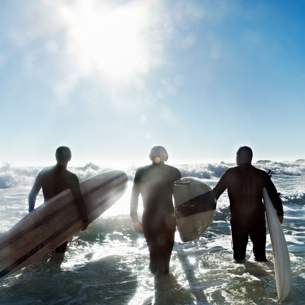 a group of surfers walk through the water