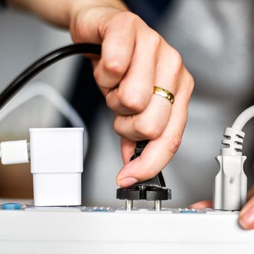 person plugging in cord to surge protector