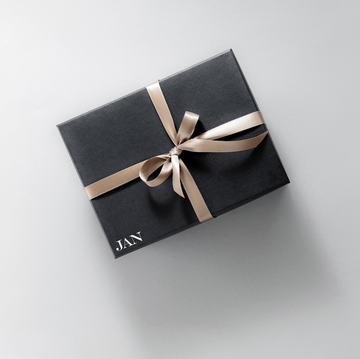 one gift wrapped in dark black paper with luxury bow on pastel background horizontal with copy space banner
