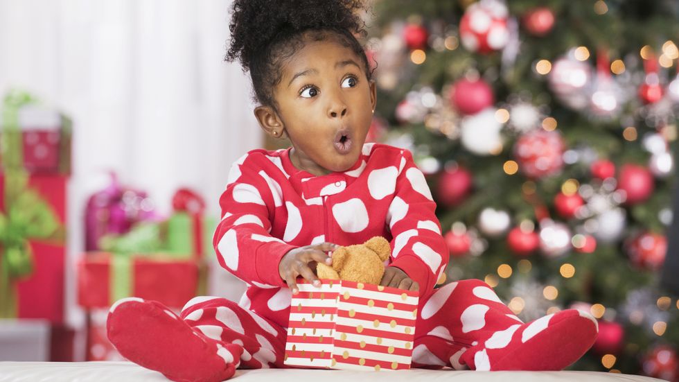 Surprised Black girl holding teddy bear toy on Christmas