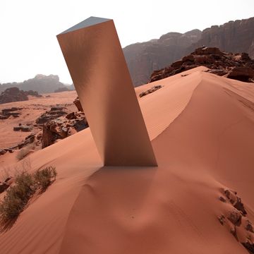 surreal metallic monolith prism in the middle of the sand dune desert