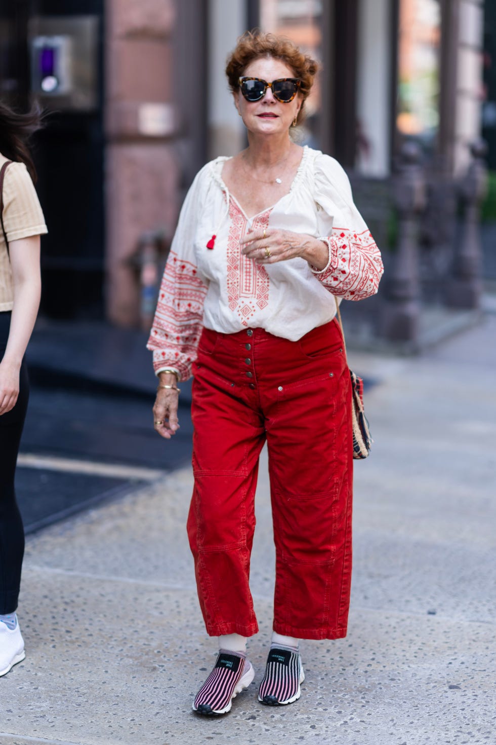 susan sarandon con blusa mexicana, pantalones rojos y zapatillas deportivas