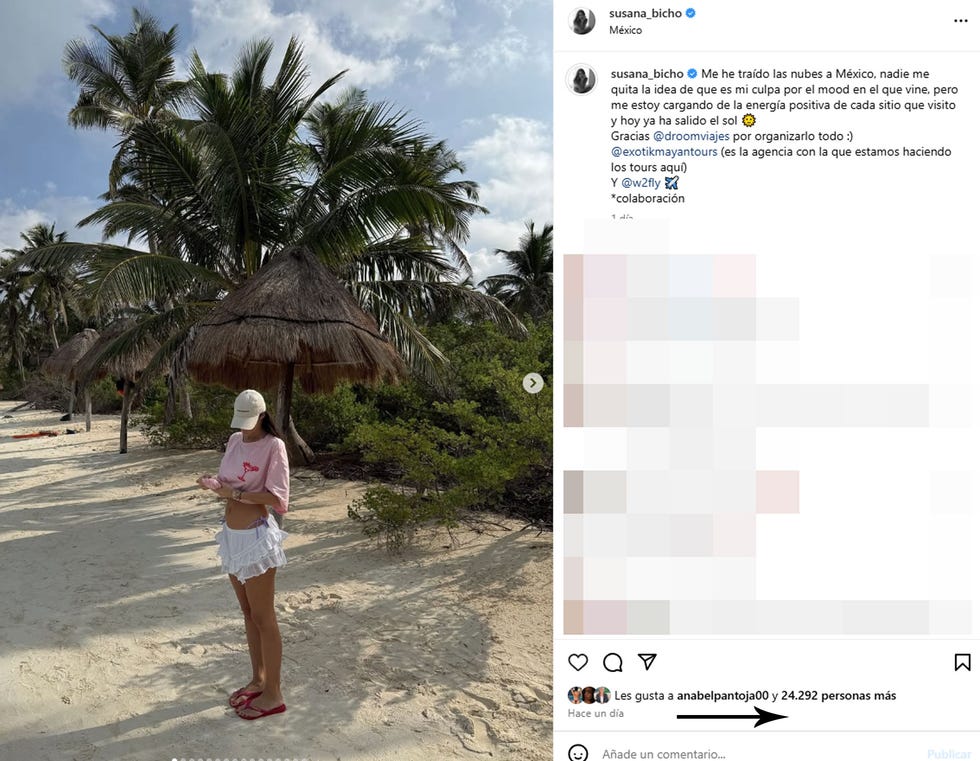 a woman stands on a sandy beach surrounded by palm trees and a thatched shelter