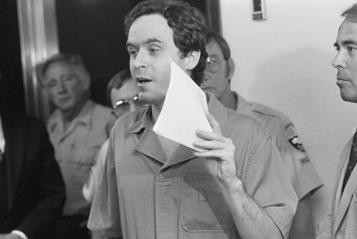 ted bundy holding a piece of paper in front of his face in court