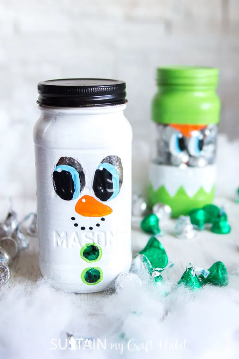 mason jar painted white to look like a snowman with hershey's kisses laying around the jar