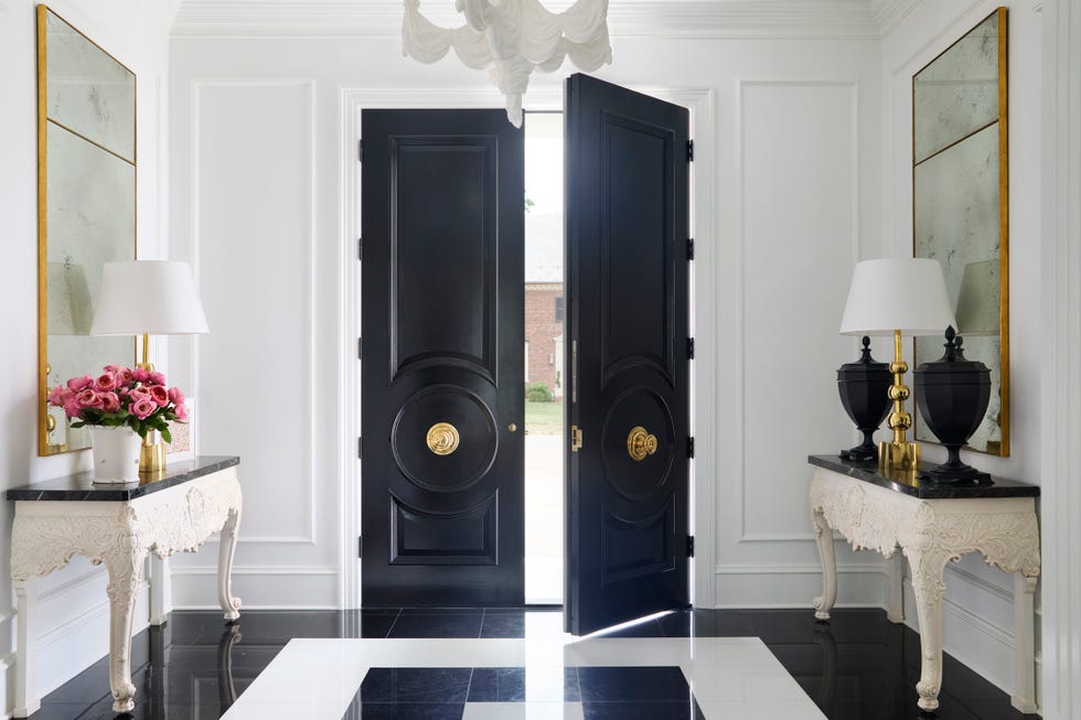 foyer with open double black doors and a table on each side with art above it