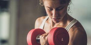 Sweaty athletic woman exercising with dumbbells in a health club.