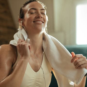 sweaty athletic woman listening music over earphones at home