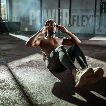 Sweaty black athlete doing sit-ups in a gym.