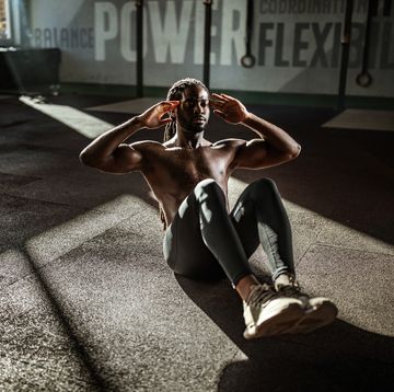 sweaty black athlete doing sit ups in a gym