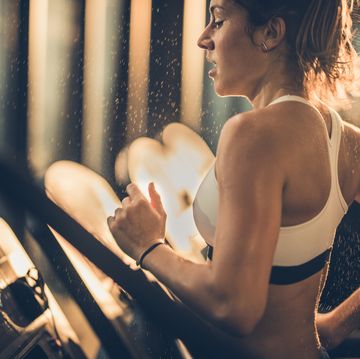 sweaty woman running on treadmill during sports training in a gym